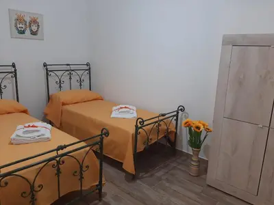 two beds in a room with a vase of flowers at Casa vacanze Il Girasole in Bagheria