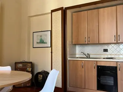 a kitchen with wooden cabinets and a table with white chairs at La casa del Maestro in Palermo