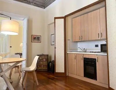 a kitchen with wooden cabinets and a table and a dining room at La casa del Maestro in Palermo