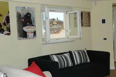 a living room with a black couch and two windows at Prince Moncada in Palermo