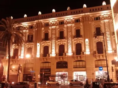 a lit up building with cars parked in front of it at Prince Moncada in Palermo