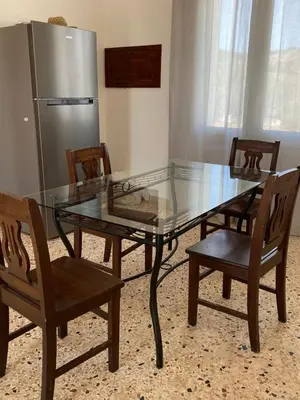 a glass table with two chairs and a refrigerator at Il Rifugio della Grotta S.Ninfa in Santa Ninfa
