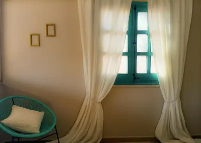 a window with a white curtain and a chair at Villemar in Isola delle Femmine