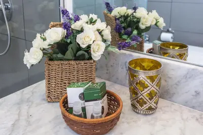 a bathroom counter with flowers in a basket and a mirror at Guascone Apartments in Palermo
