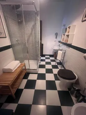 a bathroom with a shower and a black and white checkered floor at Terrazza Rosa Bianca in Palermo