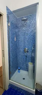 a bathroom with a shower with a blue tile wall at Appartamento Salinas Palermo in Palermo