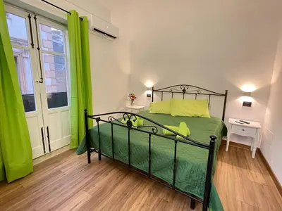 a bedroom with a bed with green sheets and a window at A'nicaredda (la piccolina) in Castellammare del Golfo