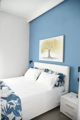 a bedroom with a white bed and a blue wall at Al Massimo apartment in Palermo