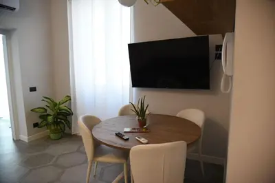 a dining room table with chairs and a television on a wall at Al Massimo apartment in Palermo