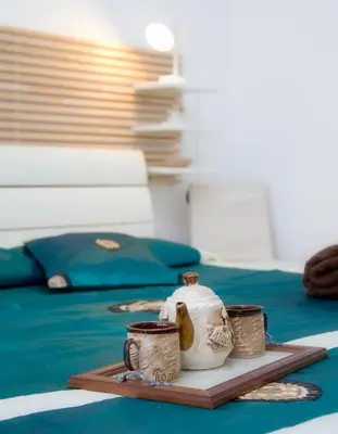 a tray with three cups and a vase on a bed at King's Residence in Balestrate