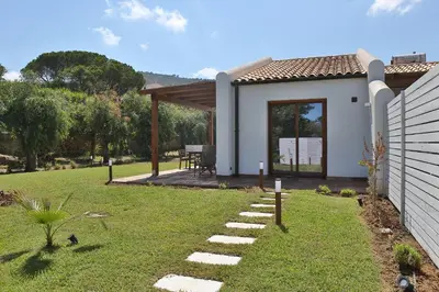 a small white house with a patio and grass at Villa Memi in Cefalù
