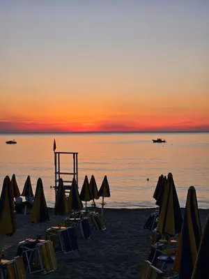 a group of umbrellas and chairs on a beach at sunset at IsolaHome in Isola delle Femmine