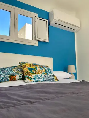 a bedroom with blue walls and a bed with pillows at A casa di Alex in Palermo