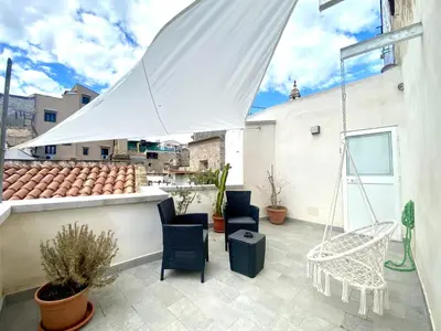 a patio with chairs and a white umbrella at A casa di Alex in Palermo