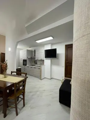 a living room with a table and a kitchen at Civico 356 in Castellammare del Golfo