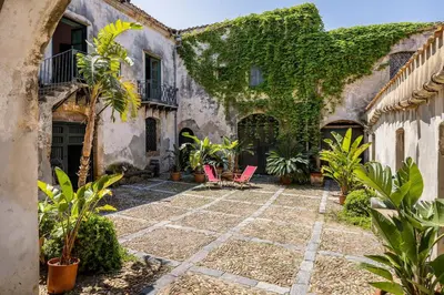 a courtyard of an old house with plants and chairs at Villa surrounded by Nature overlooking the Sea - Cefalù in Lascari
