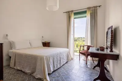 a bedroom with a bed and a table and a window at Villa surrounded by Nature overlooking the Sea - Cefalù in Lascari