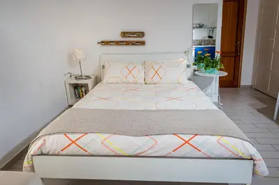 a bedroom with a white bed with a colorful bedspread at Veranda sul Porticciolo in Castellammare del Golfo
