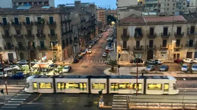 a white tram on a city street with cars at Antadia in Palermo