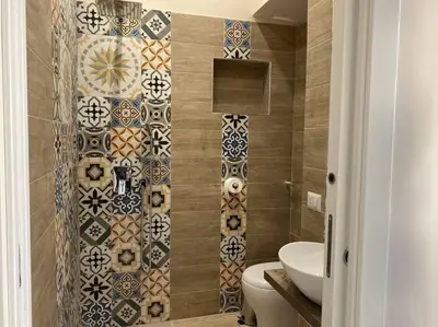 a bathroom with a toilet and a tiled wall at DEMMA LUXURY HOME in Palermo