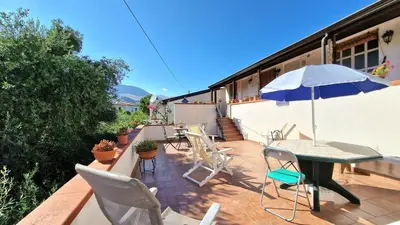 a patio with a table and chairs and an umbrella at Appartamenti Amagea in Scopello