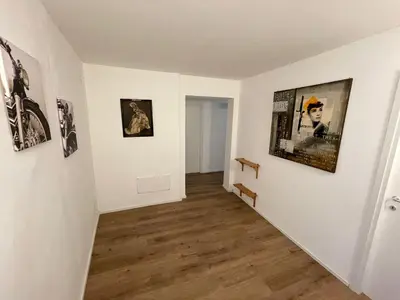 a hallway with a white wall with pictures on it at A CASA DI ELENA in Palermo