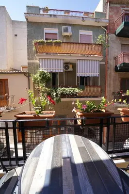 a table and chairs on a balcony with a building at Regina Stella in Lascari
