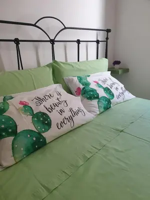 a bed with green sheets with cactus pillows on it at Le Due Perle in Palermo