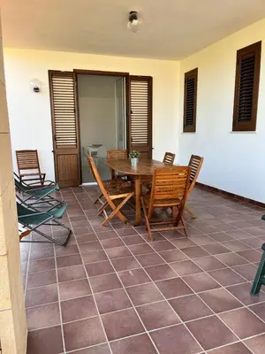 a patio with a wooden table and chairs at Villa Capri Holiday Home in Campofelice di Roccella