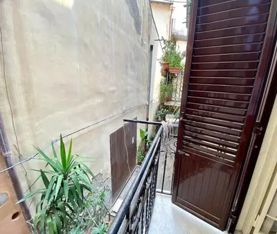 a balcony with a wooden door and some plants at Santa Cecilia House centro Palermo-350 mt stazione in Palermo