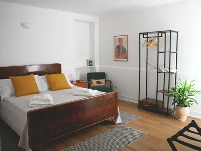 a bedroom with a bed with yellow pillows and a chair at Il corvo e la volpe in Palermo