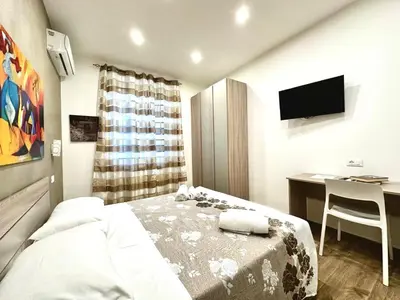 a bedroom with a bed and a desk and a television at MD APARTAMENT CORAL BAHLARA in Palermo