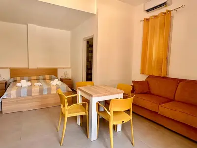 a living room with a bed and a table and chairs at Summer Vibes in Castellammare del Golfo