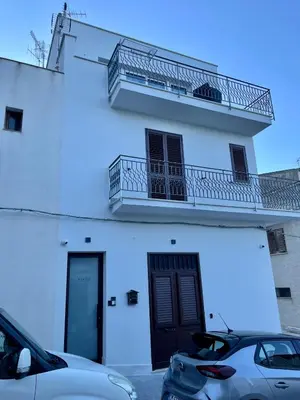 a white building with two cars parked in front of it at Summer Vibes in Castellammare del Golfo
