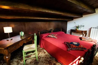 a bedroom with a bed with a desk and a red bedspread at Casa Margaret in Collesano