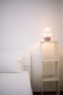 a white bed with a lamp on a white shelf at La Casa al mercato - SELF CHECK-IN in Palermo