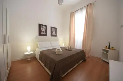 a white bedroom with a bed and a window at Nigra Apartments in Palermo