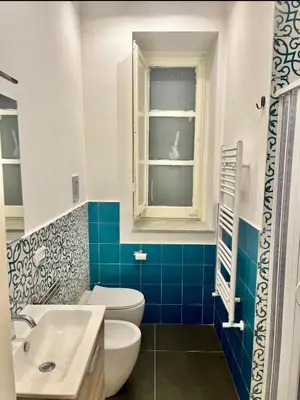 a bathroom with a toilet and a sink and a window at Nigra Apartments in Palermo