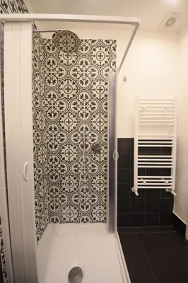 a bathroom with a shower door with a patterned wall at Nigra Apartments in Palermo