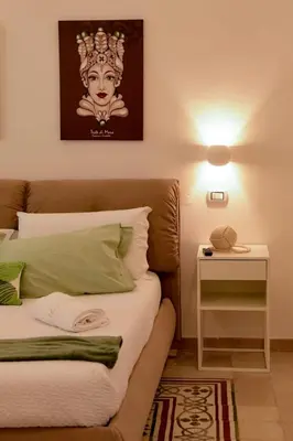 a bedroom with a bed and a side table with a lamp at Madre Terra Airport Apartment & Rooms in Terrasini