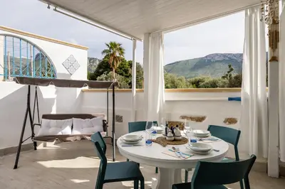 a dining room with a table and chairs and a large window at Madre Terra Airport Apartment & Rooms in Terrasini