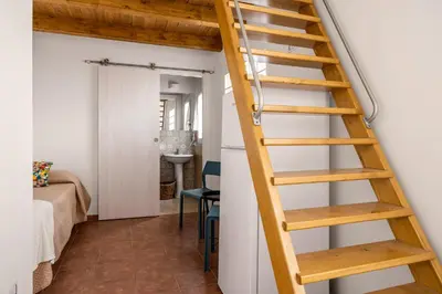 a ladder leading up to a room with a table at Madre Terra Airport Apartment & Rooms in Terrasini