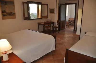 a room with two beds and a table with a dining room at Punto de Vista B&B Makari in San Vito lo Capo
