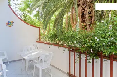 a white table and chairs in a room with plants at Villa Verdemare in San Vito lo Capo