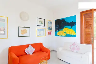 a living room with an orange couch and a white chair at Villa Verdemare in San Vito lo Capo