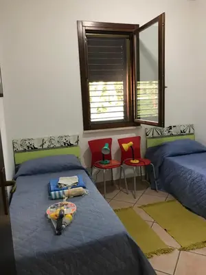 a bedroom with two beds and two chairs and a window at Casa al mare a Campofelice di Roccella - Cefalù in Lascari