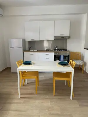 a kitchen with a white table and yellow chairs at Casa di Leda in Santa Flavia