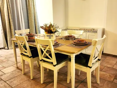 a dining room table with chairs and a table and a kitchen at Alvarado - Your Home in Sicily in Carini
