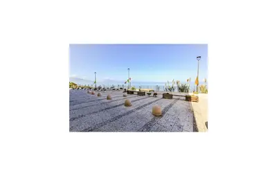 a row of benches on a beach with the ocean in the background at Beautiful Apartment In Trappeto in Trappeto