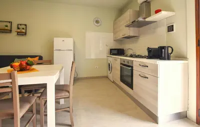 a kitchen with a table and a white refrigerator at Lovely Apartment In Trappeto With Wifi in Trappeto